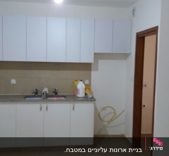 מטבח עם ארונות לבנים וכיור